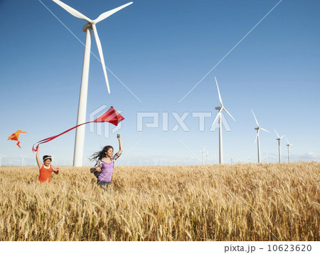 USA, Oregon, Wasco, Girls (10-11, 12-13) playing with kite in wheat field, wind turbines in background USA, Oregon, Wasco, Girls (10-11, 12-13) playing with kite in wheat field, wind turbines in background 10623620