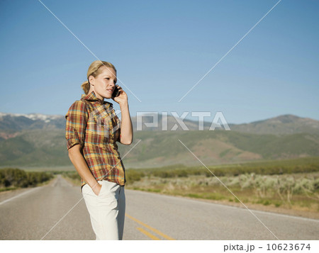 USA, Utah, Kanosh, Mid adult woman calling emergency services on empty desert road 10623674