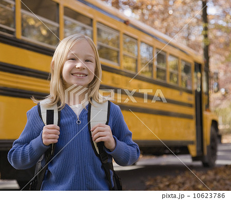 Girl with backpack in front of school bus 10623786