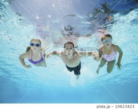 Father with two daughters (6-7,8-9) swimming underwater 10623823