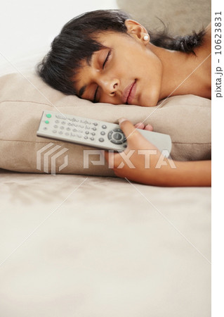 Young woman holding remote control while sleeping Young woman holding remote control while sleeping 10623831