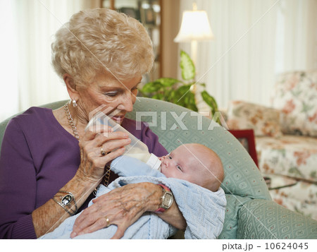 Senior woman giving milk to grandson (2-5 months) 10624045