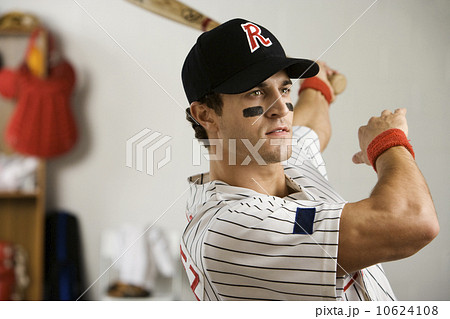Baseball player practicing swing in locker room 10624108