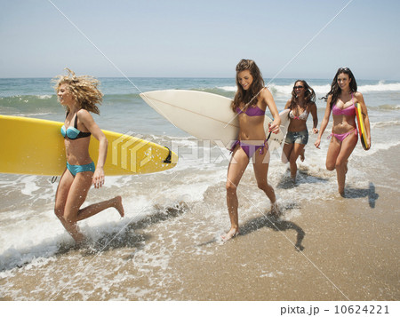 Group of young attractive women running into water with surfboards 10624221