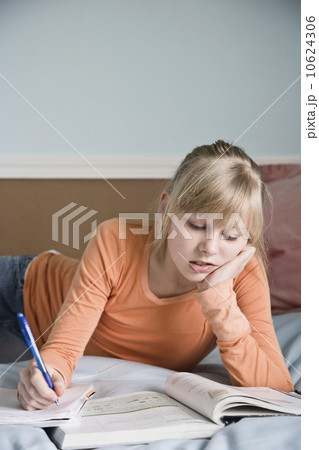 Girl doing homework on bed 10624306