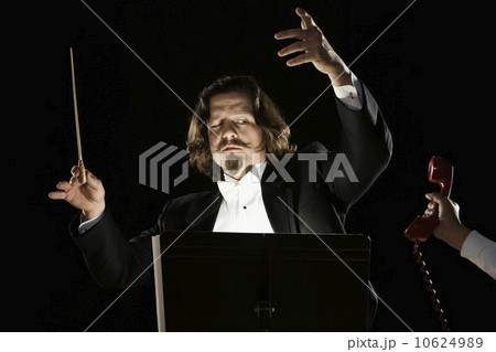 Telephone being handed to orchestral conductor 10624989