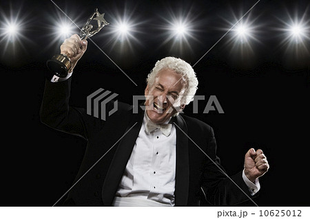 Man in tuxedo holding trophy 10625012