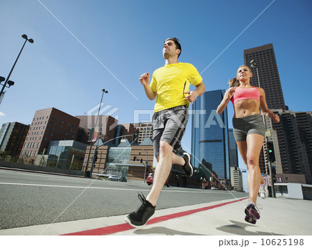 USA, California, Los Angeles, Young man and young woman running on city street 10625198