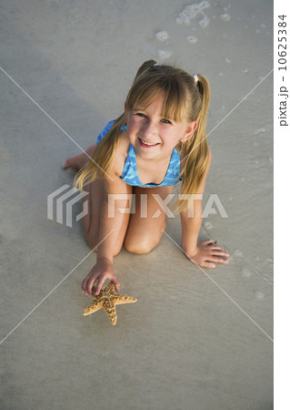 Girl picking up starfish, Florida, United States Girl picking up starfish, Florida, United States 10625384