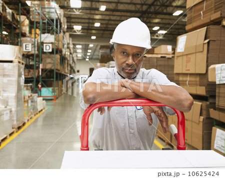 Portrait of man pushing hand truck in warehouse Portrait of man pushing hand truck in warehouse 10625424