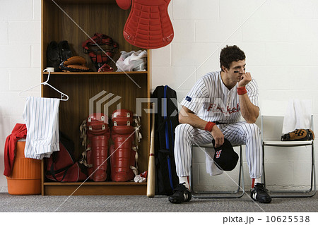 Baseball player sitting in locker room looking pensive Baseball player sitting in locker room looking pensive 10625538