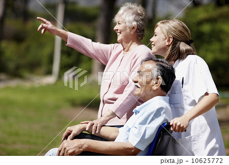 Two woman out for a walk with man in a wheelchair 10625772