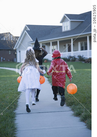 Children in Halloween costumes skipping on sidewalk Children in Halloween costumes skipping on sidewalk 10625905