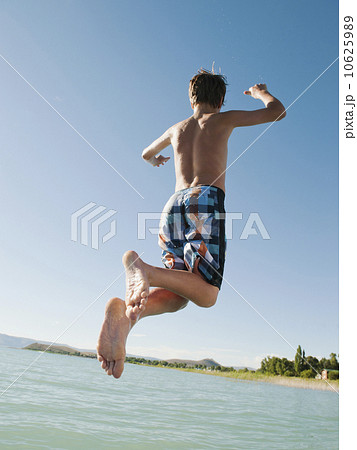 Boy (12-13) jumping into lake 10625989
