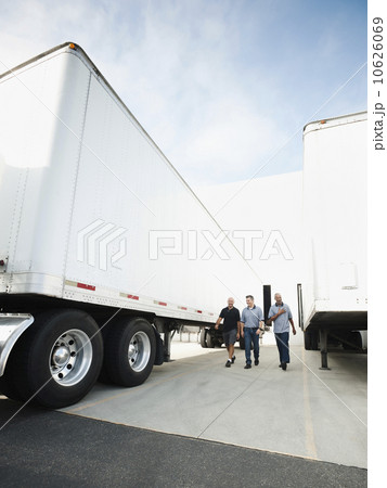 Three men walking between trucks 10626069