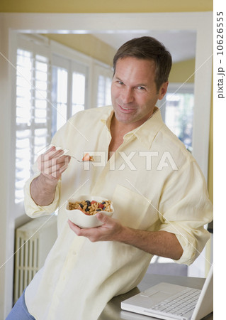Man eating cereal in kitchen 10626555