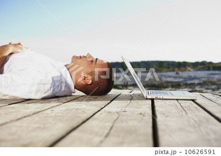 Man sleeping next to laptop on dock Man sleeping next to laptop on dock 10626591