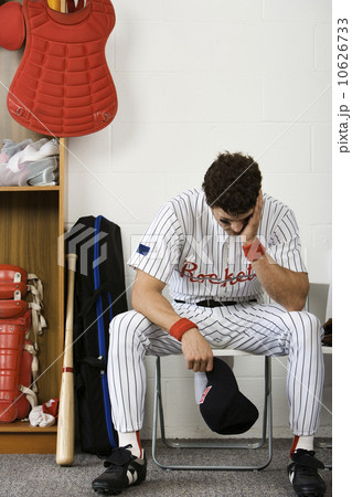 Baseball player sitting with head in hands in locker room Baseball player sitting with head in hands in locker room 10626733