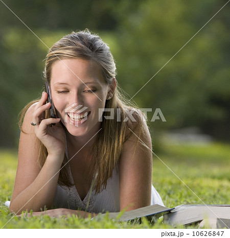 College student reading in grass and talking on cell phone 10626847
