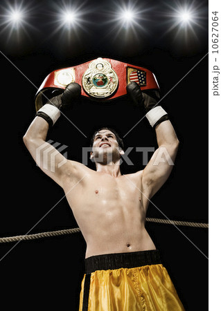 Boxer holding championship belt overhead in boxing ring Boxer holding championship belt overhead in boxing ring 10627064