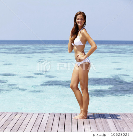 Young woman in bikini standing on jetty 10628025