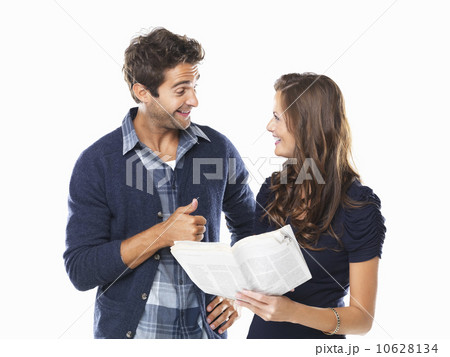 Studio shot of young couple with newspaper smiling and looking at each other 10628134