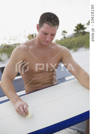 Man waxing surfboard 10628190