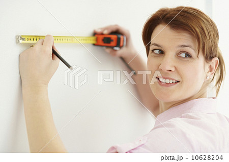 Woman using measuring tape Woman using measuring tape 10628204