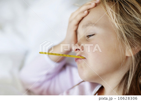 Sad girl (10-11) lying in bed with thermometer in mouth Sad girl (10-11) lying in bed with thermometer in mouth 10628306