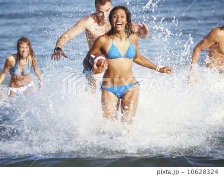 Young friends playing football in ocean 10628324
