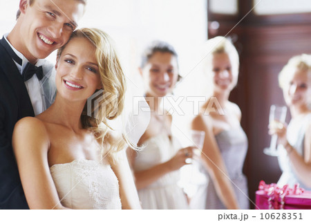 Portrait of newly wed couple, bridesmaids in background 10628351