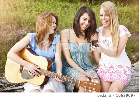Three young women with guitar and cell phone relaxing Three young women with guitar and cell phone relaxing 10629097
