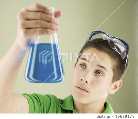 Boy looking at beaker of liquid 10629175