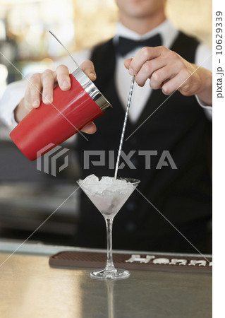 Young bartender pouring cocktail Young bartender pouring cocktail 10629339