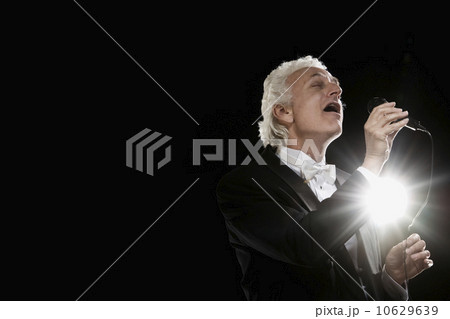 Man in tuxedo singing into microphone 10629639