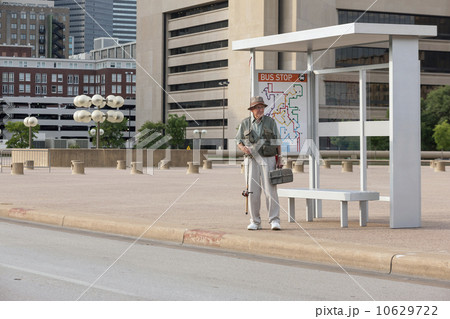 Senior man standing at bus stop with fishing rod 10629722