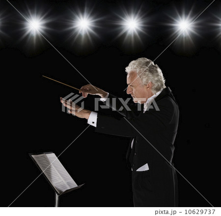 Man in tuxedo conducting under lights 10629737