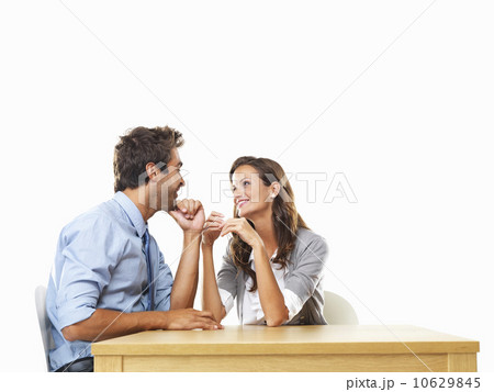 Business couple sitting at table with hands close to each other and smiling 10629845