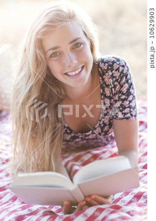 Happy teenage girl (16-17) reading book outdoors 10629903