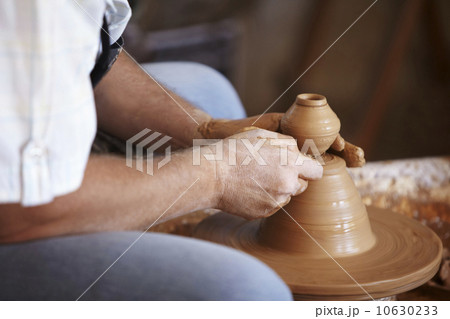 Hands working with clay on potter's wheel 10630233