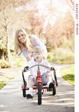 Mother and son (2-3) riding tricycle in park Mother and son (2-3) riding tricycle in park 10630458