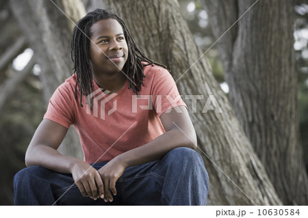 Teenage boy (16-17) with dreadlocks, sitting in park Teenage boy (16-17) with dreadlocks, sitting in park 10630584