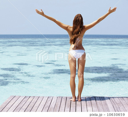 Young woman in bikini standing on jetty 10630659