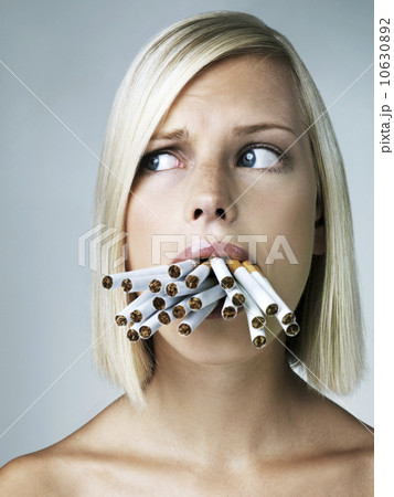 Studio portrait of young woman with mouthful of cigarettes 10630892