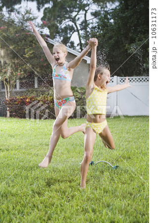Girls running through sprinklers 10631173