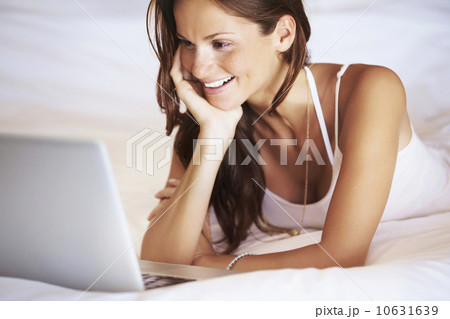 Woman using laptop while lying in bed 10631639