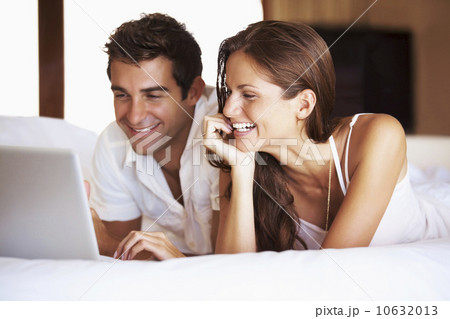 Couple using laptop while lying in bed Couple using laptop while lying in bed 10632013