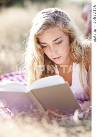 Teenage girl (16-17) reading book outdoors 10632156