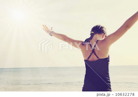 Rear view of girl (8-9) standing with arms raised 10632278
