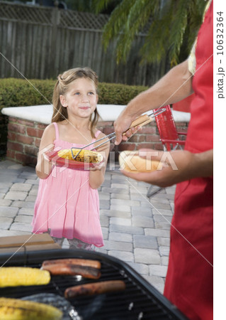 Father at barbecue grill serving daughter hot dog 10632364